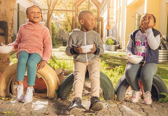 playful children eating from bowls in a park