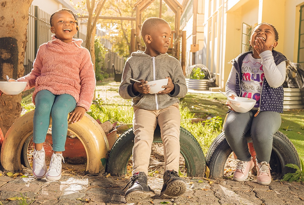 playful children eating from bowls in a park
