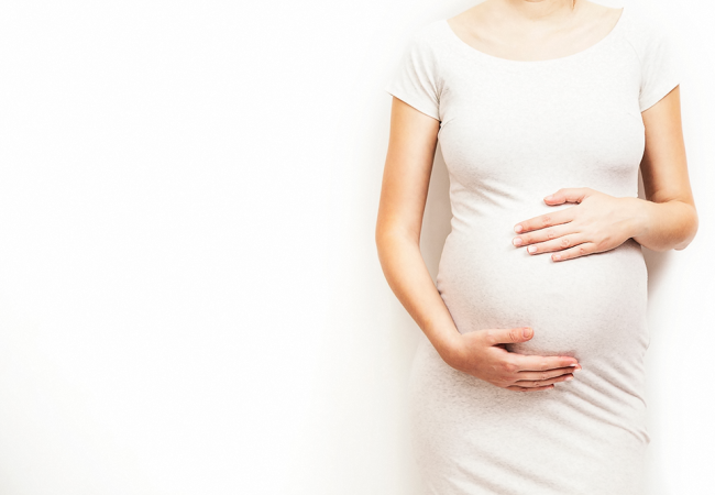 pregnant woman in a white dress holding tummy